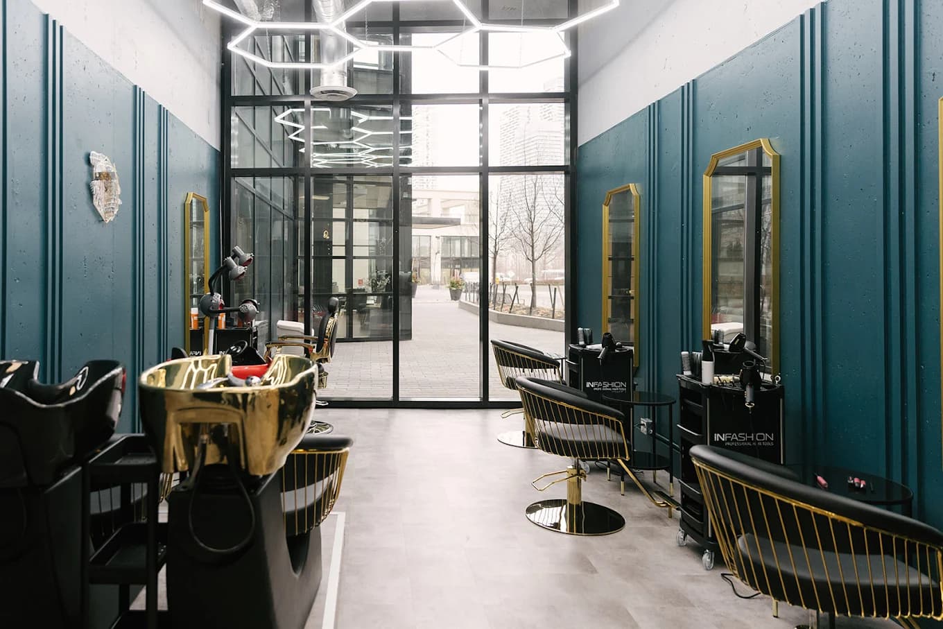 The AP Beauty Studio salon floor, with gold wash basins, black and gold styling chairs, and teal panelled walls under hexagonal lighting
